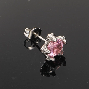 Makroaufnahme von Drachenkrallen-Ohrring mit ovalem rosa Edelstein auf schwarzem Glas