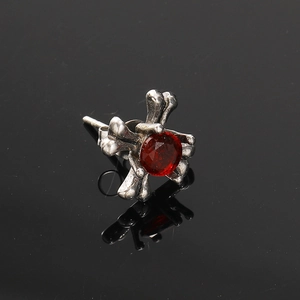 Gotische kruisbeen oorknopje in vintage zilver met een centrale rode zirkoonsteen
