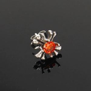 Macro-opname van vintage kruisoorbel met oranje zirkoon op een reflecterende zwarte wand