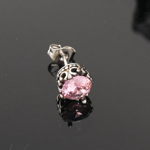 Détail macro d'un clou d'oreille rétro en acier avec zircon rose et fermoir papillon
