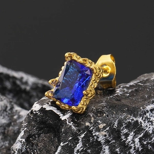 Makroaufnahme von quadratischem blauem Zirkon-Ohrstecker mit strukturierter Goldfassung
