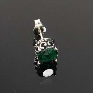 Gros plan sur un clou d'oreille vintage en titane avec zircon vert et motifs filigranes