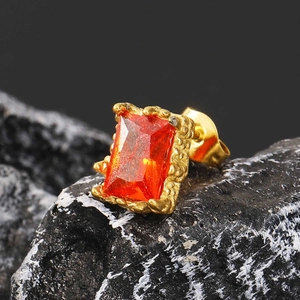 Makroaufnahme quadratischer orangefarbener Zirkonia Ohrstecker auf schwarzem Vulkanstein