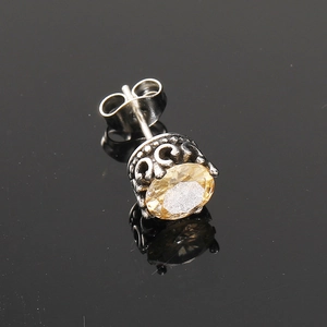 Gros plan détaillé d'un clou d'oreille vintage en forme de couronne avec gemme jaune