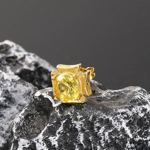 Close-up of vintage gold-plated ring with a large faceted yellow zircon on a dark rock surface