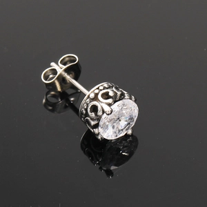Macro détaillée de boucle d'oreille vintage en acier titane avec zircon et gravures ornementales