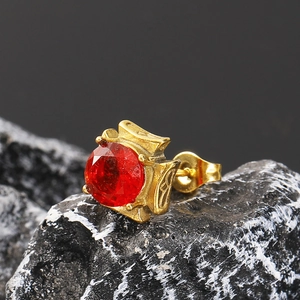 Macro detail of vintage gold stud earring with red round zircon on dark stone