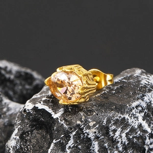 Macro detail of gold oval earring with champagne zircon on volcanic rock texture
