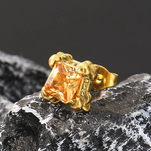 Nahaufnahme gotischer Gold-Ohrring mit quadratischem Zirkon auf dunklem Mineralstein