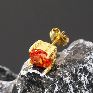 Detalle macro de pendiente de oro con circón naranja sobre piedra mineral negra