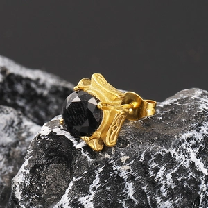Macro shot of gold stud earring with black zircon stone on natural marble base