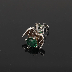Macro view of punk style wing stud earring with green faceted zircon stone