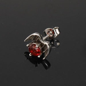 Macro detail of gothic bat wing stud earring with red zircon and silver finish