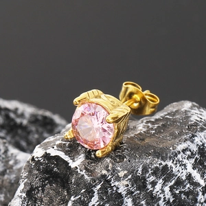 Primer plano macro de un pendiente de circonita rosa con engaste de corona dorada en piedra