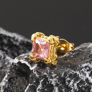Makroaufnahme eines rosa Zirkonia-Ohrrings mit goldenem Vintage-Sockel auf Stein
