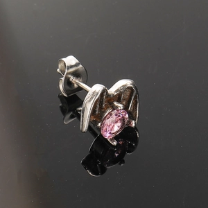 Macro shot of punk wing stud earring with pink zircon inlay and silver metal finish