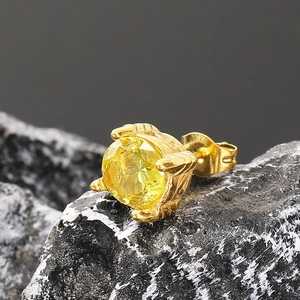 Primer plano macro de pendiente de acero inoxidable dorado con circón amarillo sobre piedra