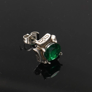 Macro detail of dark-style silver stud earring with vintage relief and green gemstone