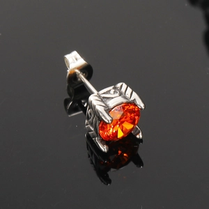 Primer plano de un pendiente vintage de plata con circón naranja y grabado detallado