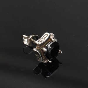 Macro detail of gothic titanium steel earring with black zircon and butterfly carvings