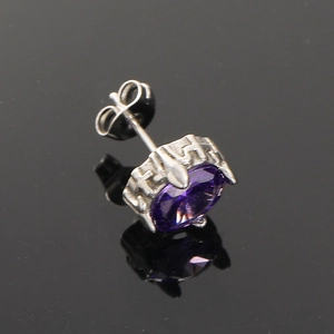 Detailed macro view of silver titanium earrings with round purple zircon and relief pattern
