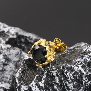 Macro shot of gold-plated titanium steel stud earring with black stone on volcanic rock