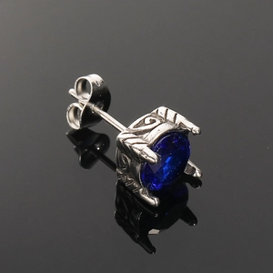 Primer plano de arete plateado vintage con circón azul real y detalles de grabado