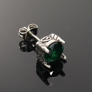 Detalle macro de pendiente de plata retro con circonita verde tallada y grabados