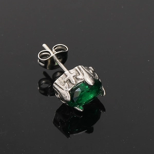 Detailed macro view of an oval emerald green zircon stud earring in retro silver steel