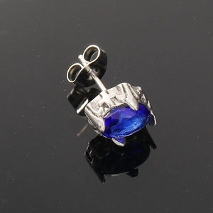 Macro shot of silver titanium stud earring featuring an oval blue zircon and side engraving