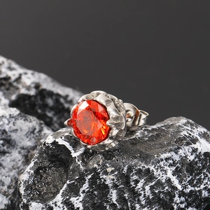 Detail of crown-set orange zircon stud earring with brilliant round cut on dark stone