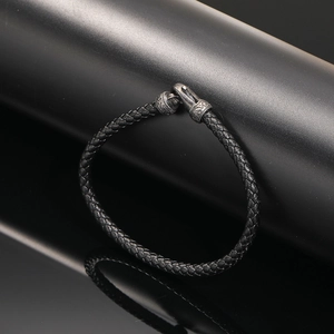 Close-up of black braided leather bracelet with vintage engraved steel magnetic clasp