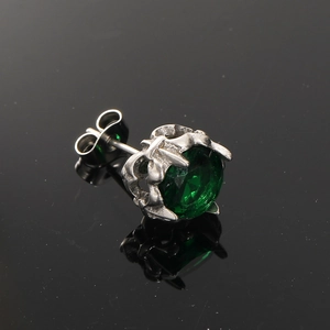 Macro shot of silver crown setting with a brilliant round-cut emerald green gemstone