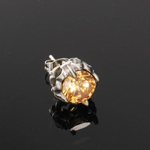 Macro shot of vintage silver stud earring with a yellow stone in a gothic claw setting