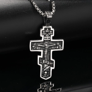 Detail of gothic stainless steel cross pendant with religious icons and relief work