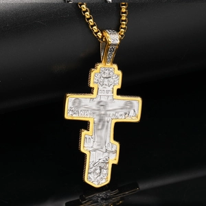 Detailed close-up of two-tone Orthodox crucifix pendant with intricate Jesus relief