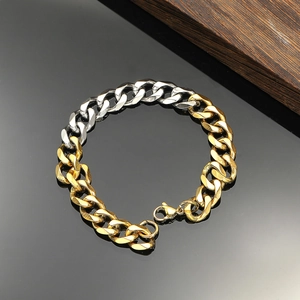 Detail eines zweifarbigen Gold- und Silber-Panzerarmbands mit Karabiner auf dunklem Holz