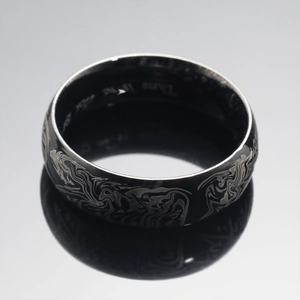 Polished black stainless steel ring with abstract silver engravings and mirror reflection