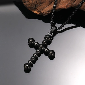 Detalle macro de collar de cruz con cuentas negras, acabado brillante y reflejo de espejo