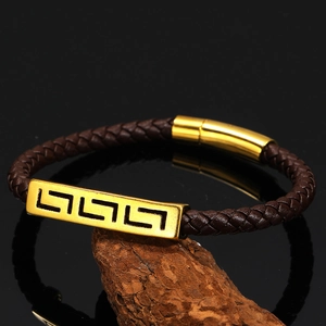Detail of braided brown leather bracelet with gold geometric Greek fret pattern