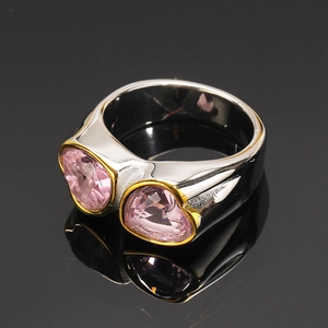 Vue macro d'une bague large argentée avec deux cœurs roses et accents dorés