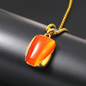 Dettaglio macro della collana in acciaio al titanio dorato con pietra occhio di gatto arancione