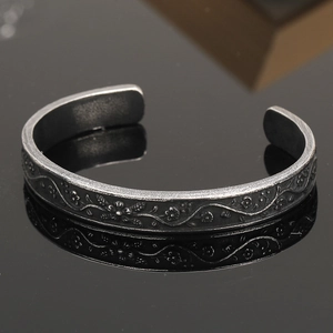 Detail of vintage silver Viking cuff featuring intricate floral vine relief patterns