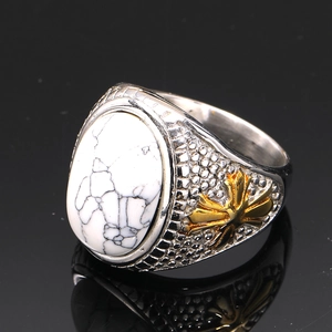 Macro shot of retro stainless steel ring with white turquoise stone and gold cross inlay