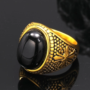 Macro shot of vintage gold-plated ring with large oval black onyx stone and engraved side