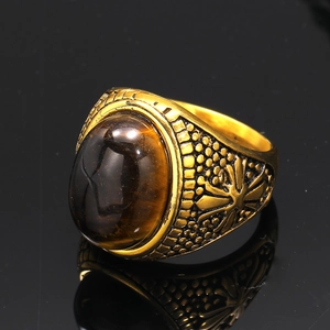 Macro shot of vintage gold men's ring with oval tiger eye stone and detailed embossing