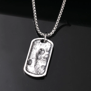 Retro punk rock skull pendant in vintage stainless steel on a black reflective background