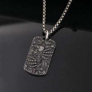 Detailed close-up of retro punk skull relief on a rectangular steel pendant necklace