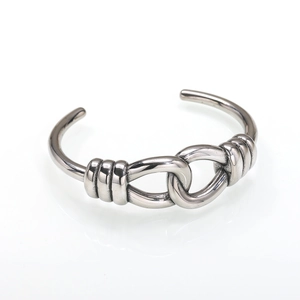 Polished stainless steel cuff bracelet with intertwined knot design on white background