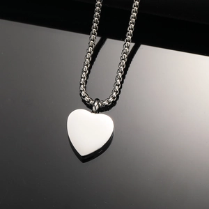 Polished silver heart-shaped perfume bottle pendant necklace on black reflective surface